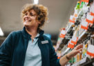 Confident businesswoman standing by the shelves and smiling in supermarket. Female manager at a grocery store.