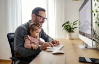 picture of father and baby enjoying the benefits of paternity leave together in front of a computer