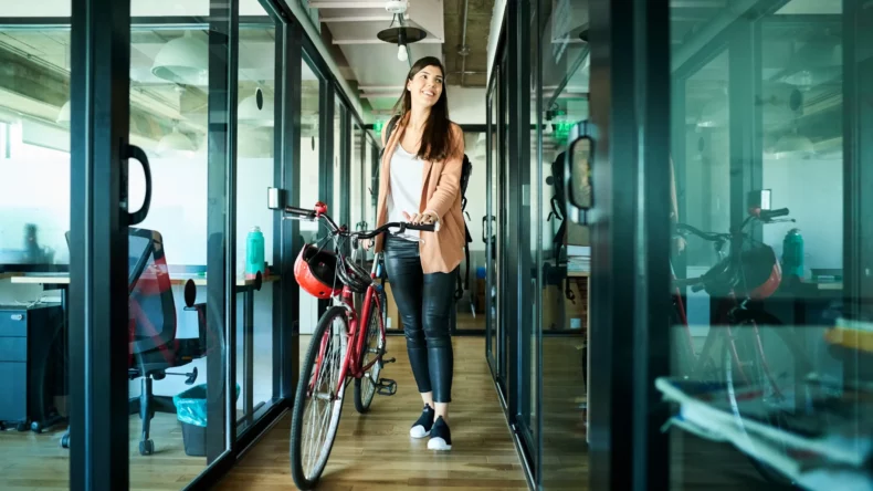 woman in office hallway with bike after returning to work from maternity leave