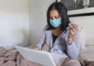woman sick in bed in front of computer sending email about her sick leave