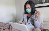 woman sick in bed in front of computer sending email about her sick leave